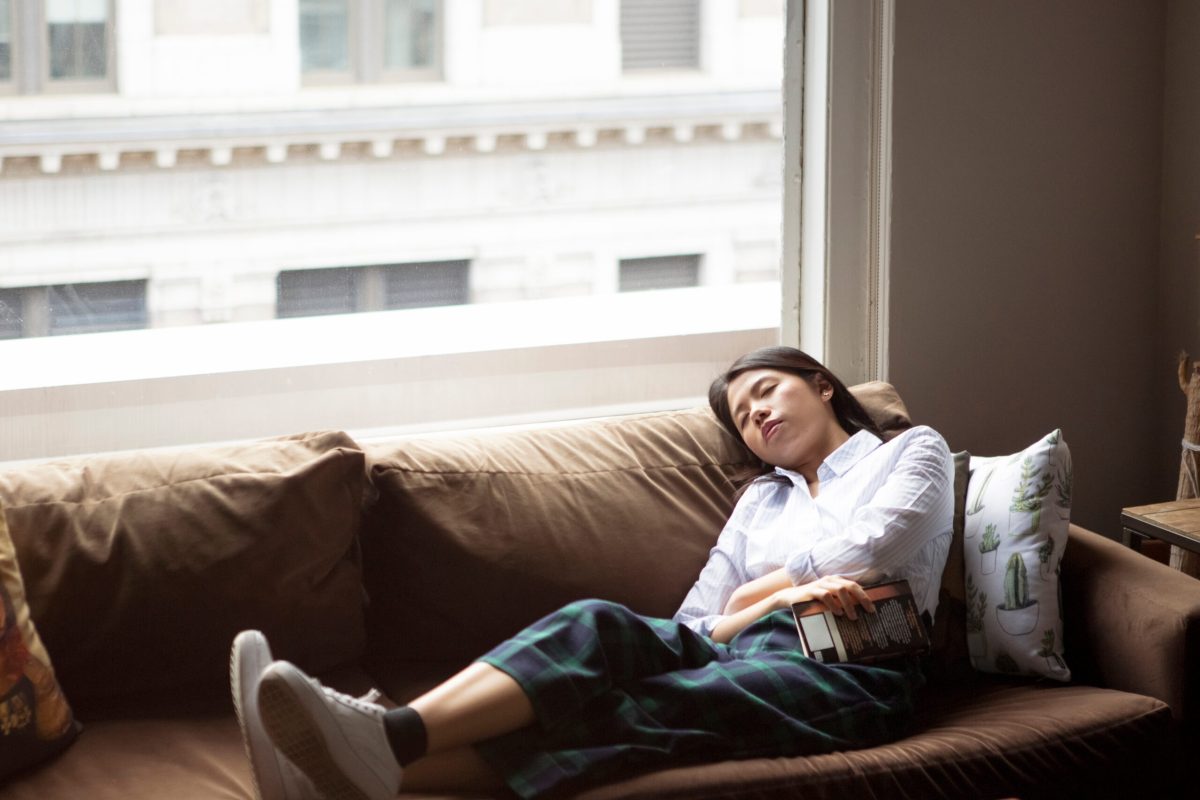High angle view of businesswoman sleeping on sofa by window in creative office