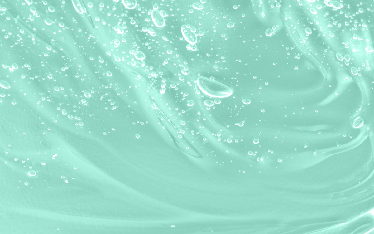 Skincare moisturizing product. Liquid green oil smudge. The concept of natural cosmetics. Hyaluronic acid clear serum sample. Aloe vera cosmetic gel texture with bubbles background. Close-up, macro.